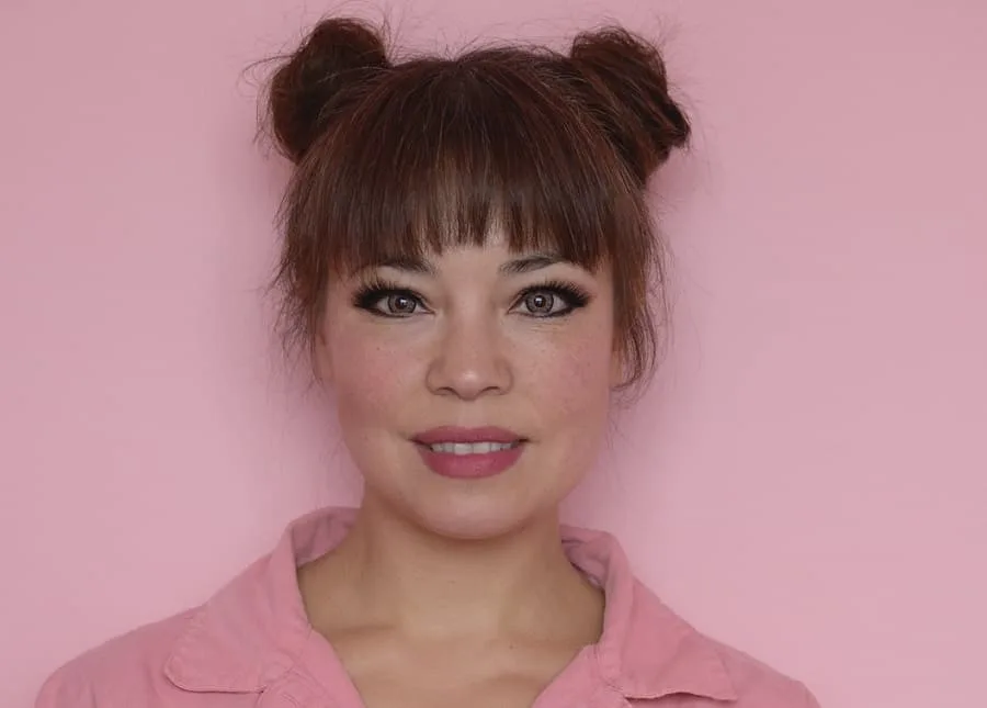 space buns hairstyle with thick bangs