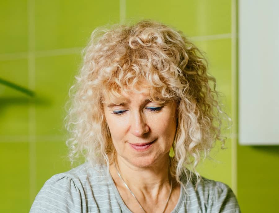 medium curly hairstyle with bangs for over 50
